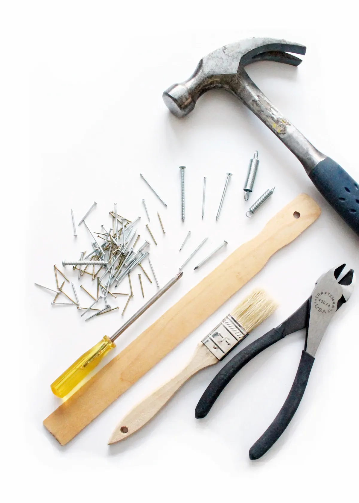 Hammer, nails and measuring tools on a white surface